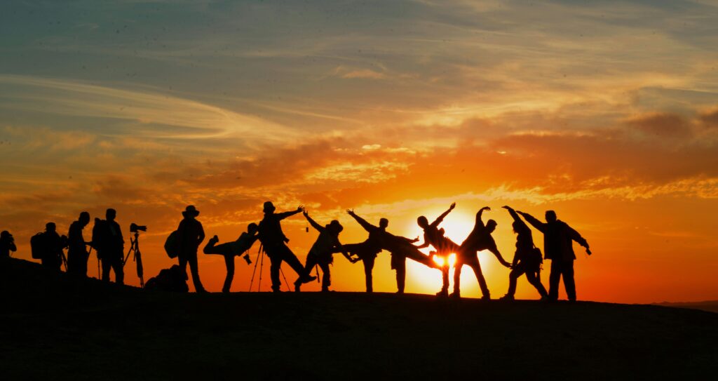 Group of people silhouetted against a vibrant sunset, showcasing unity and joy.