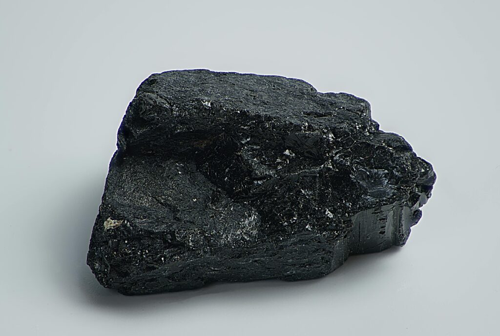 Detailed macro shot of a black mineral rock on a plain surface, showcasing texture and natural form.