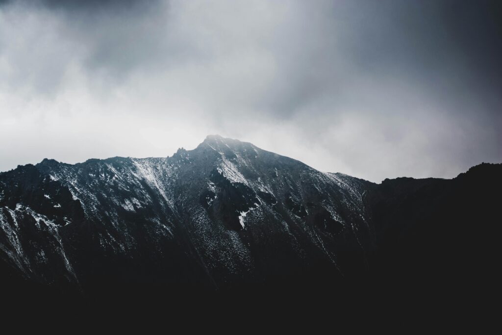 A stunning view of a snow-capped mountain peak with dramatic cloudy skies.